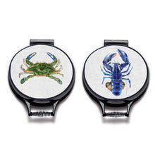 Load image into Gallery viewer, blue lobster and green crab watercolour painting on a beige linen circular aga cover with black hemming. Pictured on metal aga lid on an isolated background. Mustard and Gray