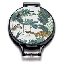 Load image into Gallery viewer, darwin's menagerie tropical print with palms, peacock, zebra, leopard painting on a beige linen circular aga cover with black hemming. Pictured on metal aga lid on an isolated background. Mustard and Gray