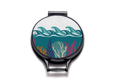 Load image into Gallery viewer, colourful terquoise waves and pink and orange seaweed print on a beige linen circular aga cover with black hemming. Pictured on metal aga lid on an isolated background. Mustard and Gray