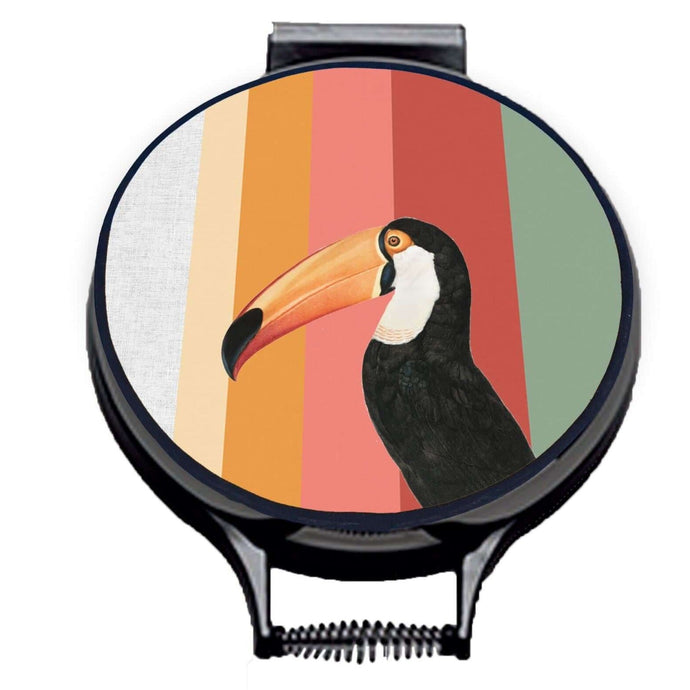 Toco Toucan illustration printwith stripes of green, red, pink and orange on beige linen circular aga cover with black hemming. Aga chef's pad hob cover. Pictured on metal aga lid on an isolated background. Mustard and Gray