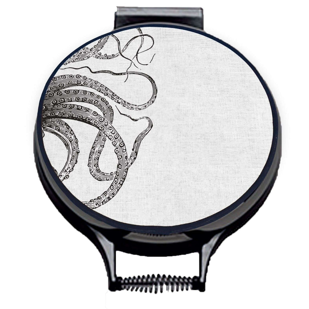 black kraken squid octocpus tenticles print on a beige linen circular aga cover with black hemming. Pictured on metal aga lid on an isolated background. Mustard and Gray