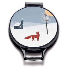 Load image into Gallery viewer, winter fox scandi modern print on a beige whith village scene including blue sky, a red fox, and church linen circular aga cover with black hemming. Pictured on metal aga lid on an isolated background. Mustard and Gray
